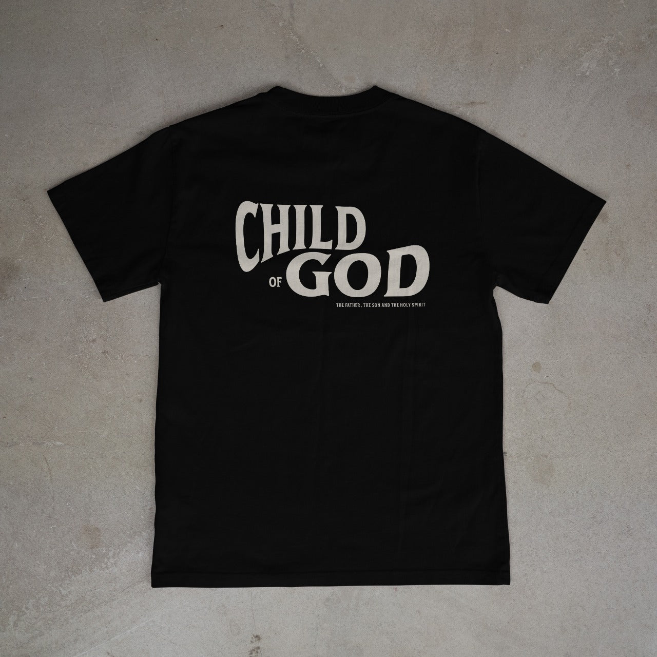 Black t-shirt with 'Child of God' text on a light gray surface